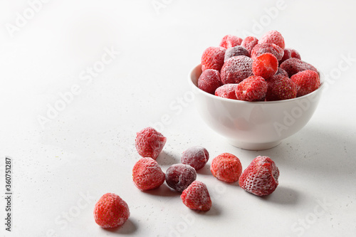 Frozen strawberries and cherry in bowl on white background. Copy space.