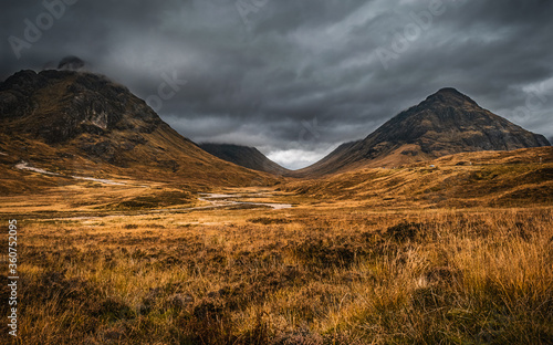 Autumn landscape in Glen Coe, Scotland, with dark clouds hanging over the peaks of Buachaille Etive Beag and Aonach Eagach. photo