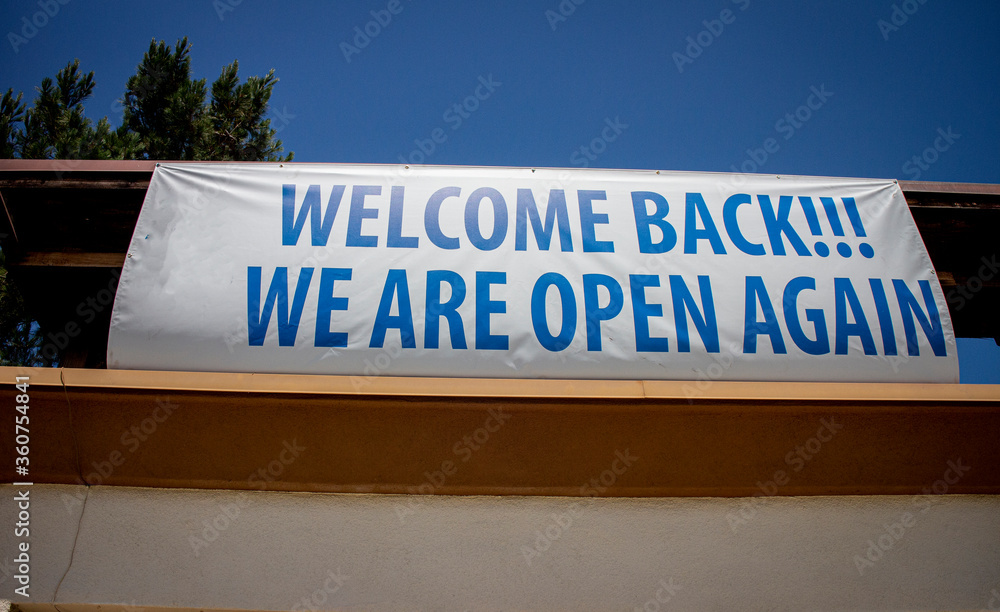 COVID-19 related sign at restaurant stating Welcome Back We Are Open Again