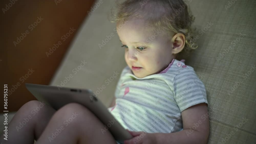 The child enthusiastically watches cartoons on the tablet, side view The child enthusiastically watches cartoons on the tablet, side view