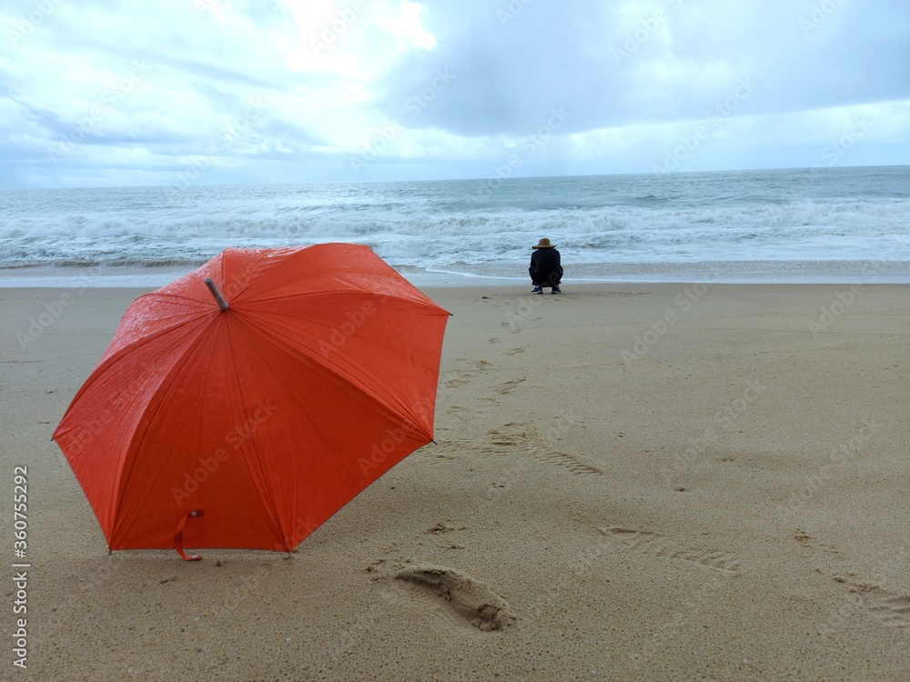 Beautiful seaside atmosphere with the life of a man and orange umbrella.