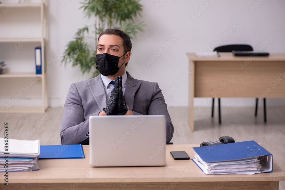 Young male employee in the office during pandemic disease