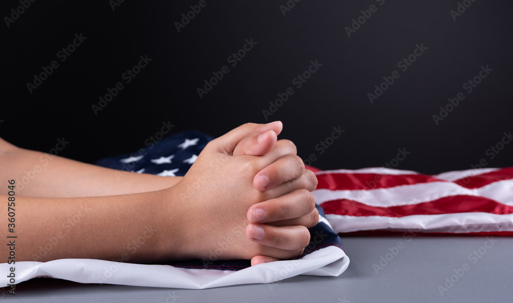 Female hands on USA flag. Woman is praying during the pandemic. Copy space text. Selective focus. Female hands on USA flag. Woman is praying during the pandemic. Copy space text. Selective focus.
