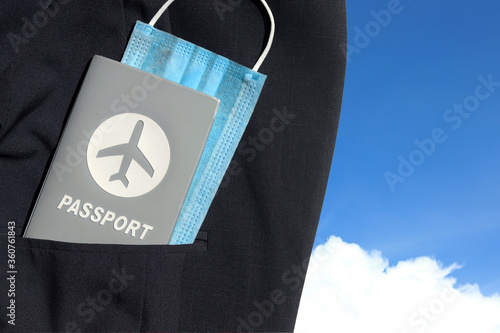 Passport with medical face mask in suit jacket pocket on blue sky background with copy space. Lifestyle and traveling concept in New Normal after Covid-19 / Coronavirus pandemic.