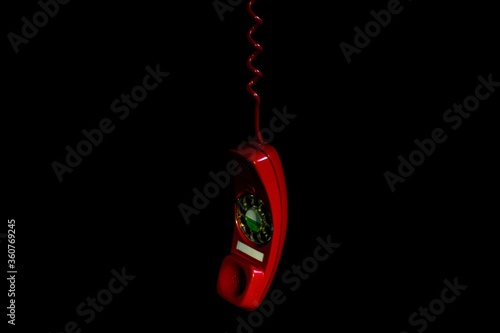 Closeup of a red phone hanging under the lights isolated on a black background photo