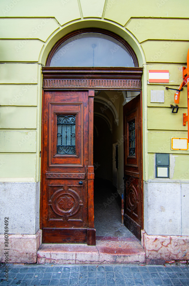Naklejka premium Elegant brown wooden door in a building with green walls, baroque style. Historical heritage in the European city of Budapest, Hungary.