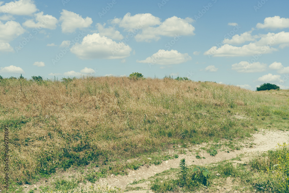 Fototapeta premium Clouds in the sky over a green hill in Texas Natural Park on a sunny June day.