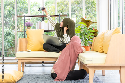 asian muslim women wear hijab selfie each other while working on sofa
