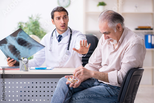 Принти на полотні Young male doctor and old patient in antismoking concept
