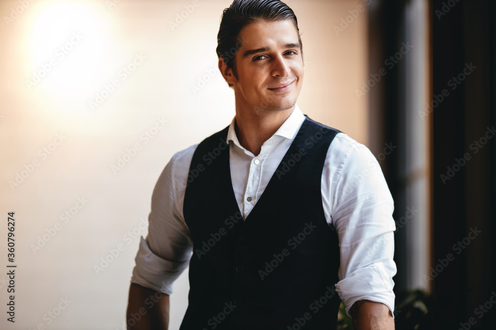 Portrait of a Smiling Caucasian Businessman, Standing by the Window and Looking into the Camera Portrait of a Smiling Caucasian Businessman, Standing by the Window and Looking into the Camera