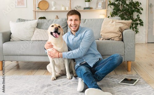 Young happy man with dog sitting on floor