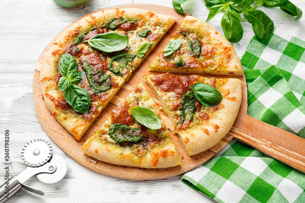 Fresh baked homemade pizza or pie with basil pesto sauce,mozzarella cheese and fresh basil leaves.