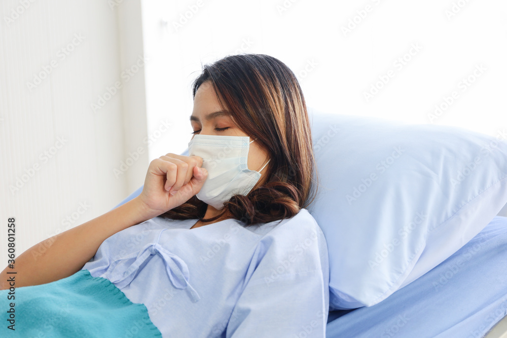 A patient woman wear face mask and cure on bed and covid-19 emergency treatment in a hospital room, curing by plasma blood A patient woman wear face mask and cure on bed and covid-19 emergency treatment in a hospital room, curing by plasma blood