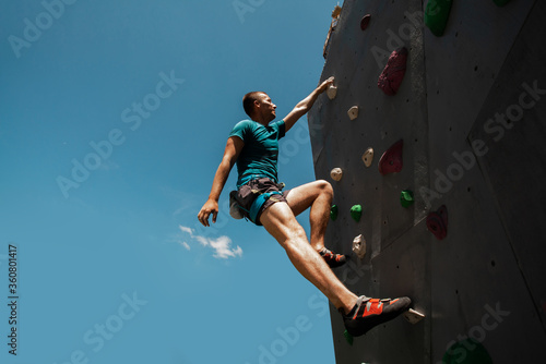 Sportsman climber on steep rock, climbing on artificial wall. Extreme sports and bouldering concept.