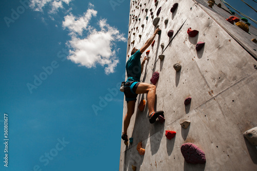 Sportsman climber on steep rock, climbing on artificial wall. Extreme sports and bouldering concept.