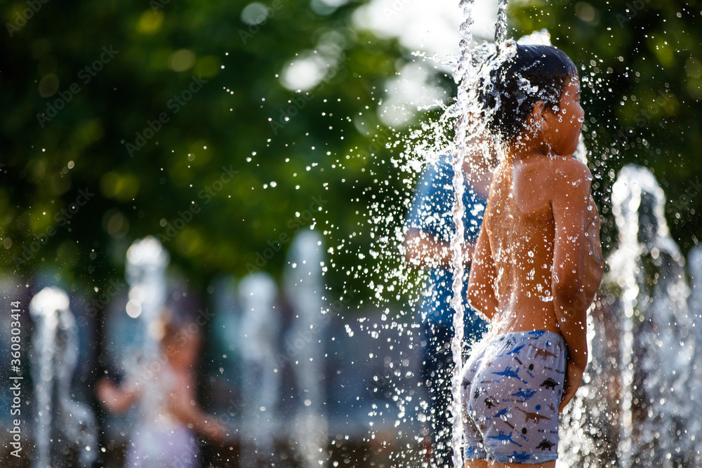 Fototapeta premium Boy playing in the fountain on a hot summer day