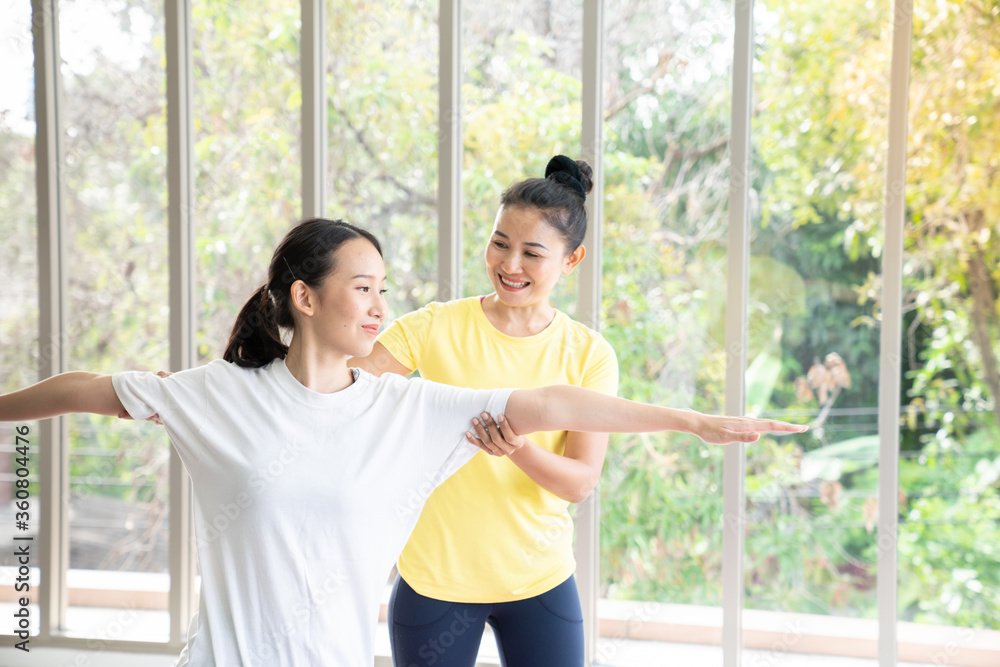 Two happy asian women in yoga poses in yoga studio with natural light setting scene / exercise concept / yoga practice / copy space / yoga studio Two happy asian women in yoga poses in yoga studio with natural light setting scene / exercise concept / yoga practice / copy space / yoga studio