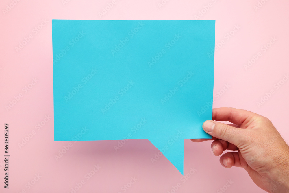 Fototapeta premium Hand holding an blue empty speech bubble on pink background