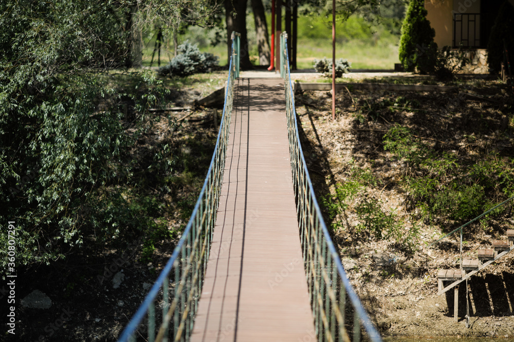 Shallow depth of field (selective focus) image with a suspension bridge above running water.