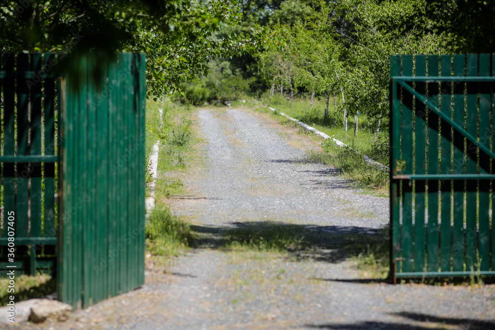 Unpaved country road leading to an open metal gate. Unpaved country road leading to an open metal gate.