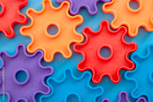Teamwork and solidarity concept with photograph of connected colorful plastic toy gears with each gear a different color isolated on blue background