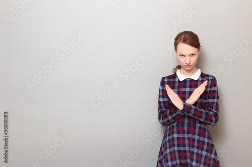 Portrait of serious girl making cross with hands, showing stop gesture