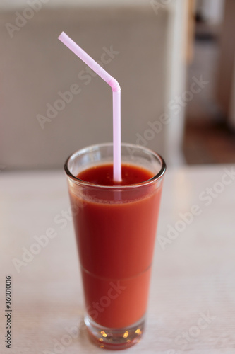 Glass of tomato juice and a drinking straw.