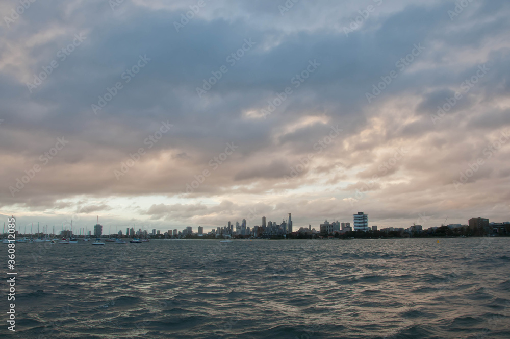 Fototapeta Wide angle evening scene of skyscrapers horizon with ocean and tall office and residential towers in Melbourne Australia