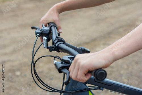 Close-up of a teenager's hands on the handlebars of a Bicycle. © Елена Николаева
