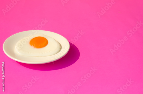 Fried egg , In white plate and pink table top.