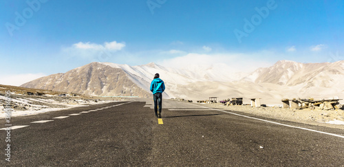A man move on a road and see view mountain in background far away.
