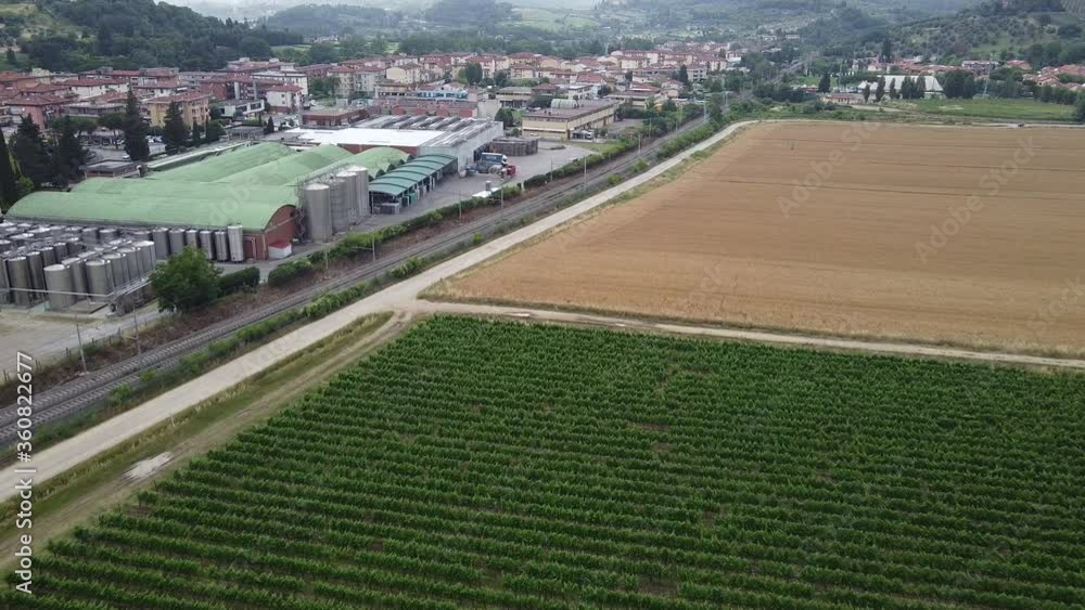 Lush Green Vineyards And Golden Fields Near The Industrial Warehouse In Le Sieci Town Of Tuscany Hills, Italy. - aerial drone. Frescobaldi headquarter Lush Green Vineyards And Golden Fields Near The Industrial Warehouse In Le Sieci Town Of Tuscany Hills, Italy. - aerial drone. Frescobaldi headquarter