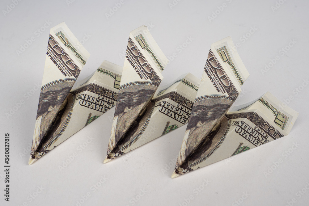 Airplanes of dollars are on the table. Airplanes made of money on a white background. Concept - a failing economic strategy. The concept is inefficient economic policy. Economic wars. A fall. Airplanes of dollars are on the table. Airplanes made of money on a white background. Concept - a failing economic strategy. The concept is inefficient economic policy. Economic wars. A fall.