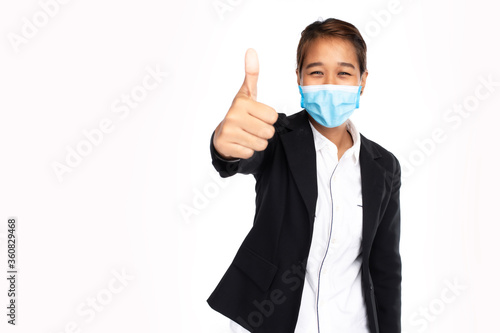 Asian businesswoman wearing surgical face mask in formal black suit jacket, show hand thumps up, looking at camera, studio lighting isolated on white background, coronavirus, COVID-19 concept