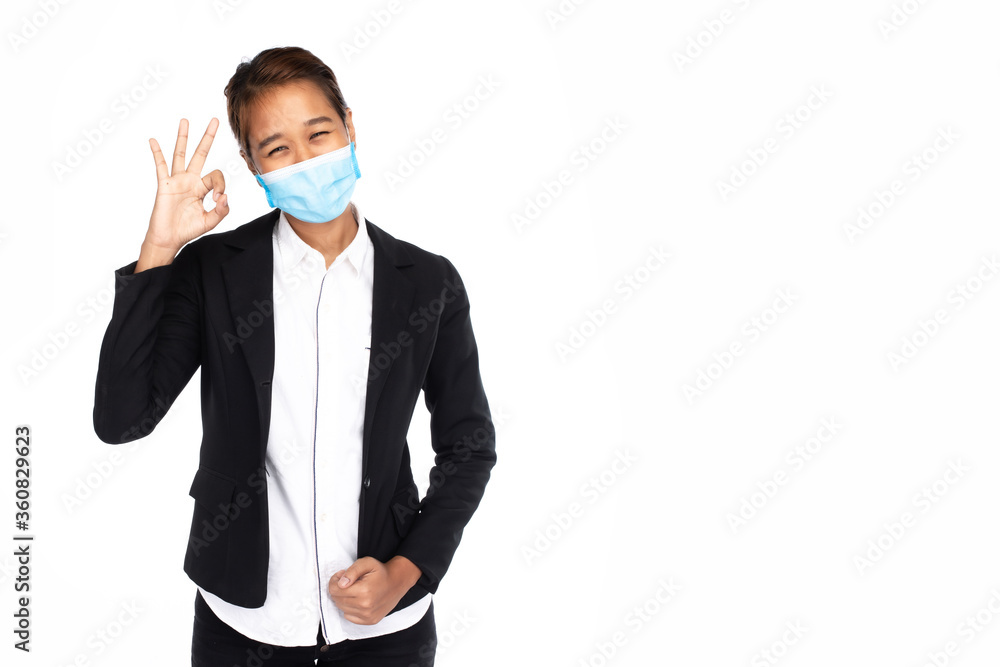 Asian businesswoman wearing surgical face mask in formal black suit jacket, show her hand symbol okay, looking at camera, studio lighting isolated on white background, coronavirus, COVID19 concept Asian businesswoman wearing surgical face mask in formal black suit jacket, show her hand symbol okay, looking at camera, studio lighting isolated on white background, coronavirus, COVID19 concept
