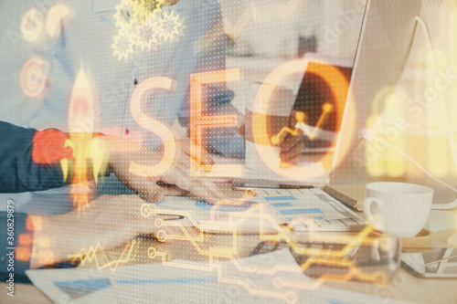 Multi exposure of seo icon with man working on computer on background. Concept of search engine optimization.