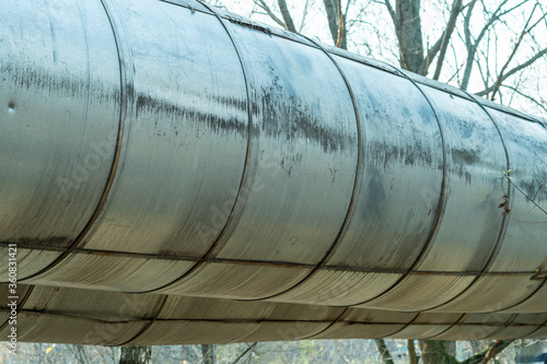 Closeup of a heating pipe. Pipeline passing through the forest against the backdrop of trees.