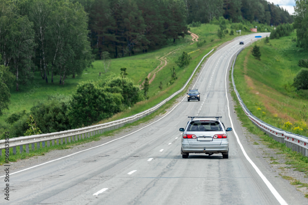 Car universal rides on an asphalt road in the background forest landscape and car traffic. The concept of moving from city to city in your car. Traveling by car Car universal rides on an asphalt road in the background forest landscape and car traffic. The concept of moving from city to city in your car. Traveling by car