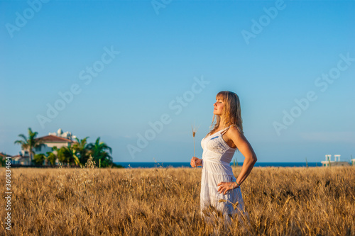 Pretty woman in white dress on the wheat field. Calm and tranquility