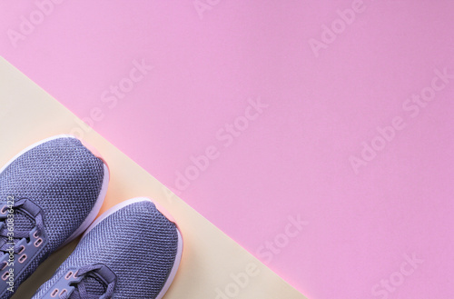 Female gray running shoes isolated on pink and yellow background with copy space. Woman sneakers for fitness. Flat lay of modern gray shoes. Top view photography. Fitness and healthy, sport concept.