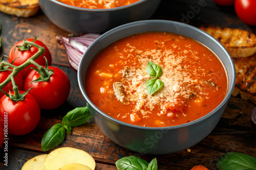 Seasonal vegetables classic minestrone soup with pasta served with cheese, grilled sour dough bread and basil leaves