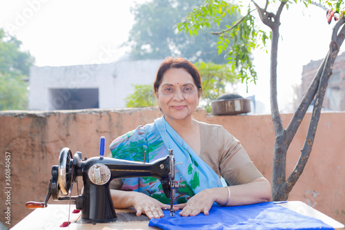Photography Indian women stitching cloths by machine at out side the home