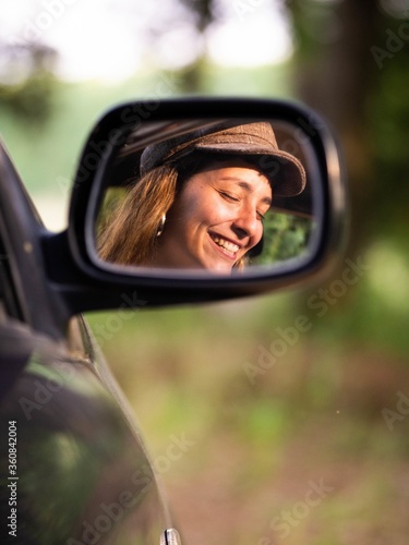 Fotografi Picture of a brunette female in a rear-view mirror with an amazing smile