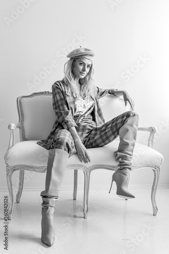 Beautiful blonde fashion woman in brow checked dress. Trendy young woman in shabby chic white interior.