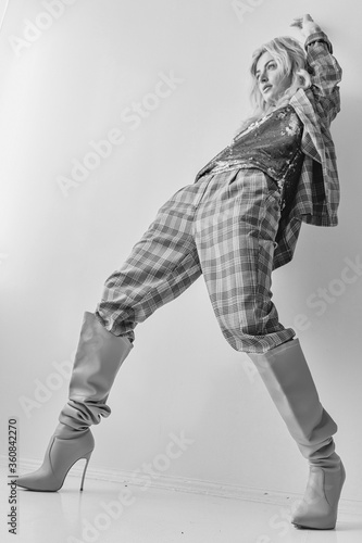 Beautiful blonde fashion woman in brow checked dress. Trendy young woman in shabby chic white interior.