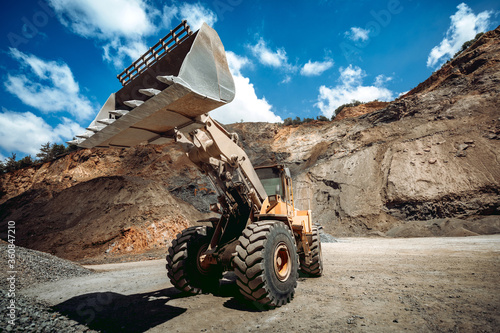 Industrial wheel loader working on construction site. Industrial machinery loading and transporting gravel against dramatic sky