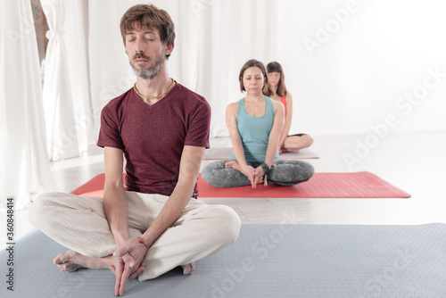 Yoga teachers sitting in the lotus position with their eyes closed. Group of people practicing Yoga. How to Keep Your Arms in the Air for a Kriya or Meditation.