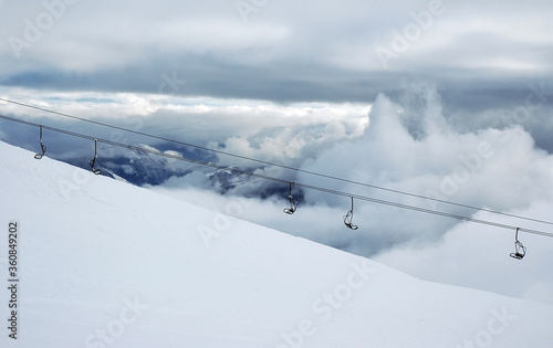 Cloudy winter mountainous landscape. View at the greater Caucasus mountain range and ski lift. Gudauri ski resort. Georgia.