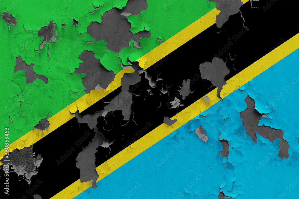 Tanzania flag close up painted, damaged and dirty on wall peeling off paint to see concrete surface. Vintage National Concept.