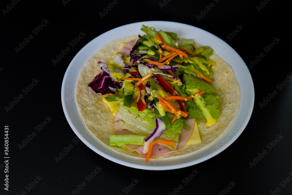 Ham, mozzarella cheese, and vegetables covered with honey mustard on flour tortilla Ham, mozzarella cheese, and vegetables covered with honey mustard on flour tortilla
